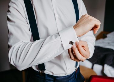 Hochzeitswahn - Ein Mann in weißem Hemd und Hosenträgern richtet vor seiner Hochzeit seine Manschettenknöpfe. Nur sein Oberkörper und seine Arme sind sichtbar; im Hintergrund ist ein Schlafzimmer zu erkennen. Oberhaus