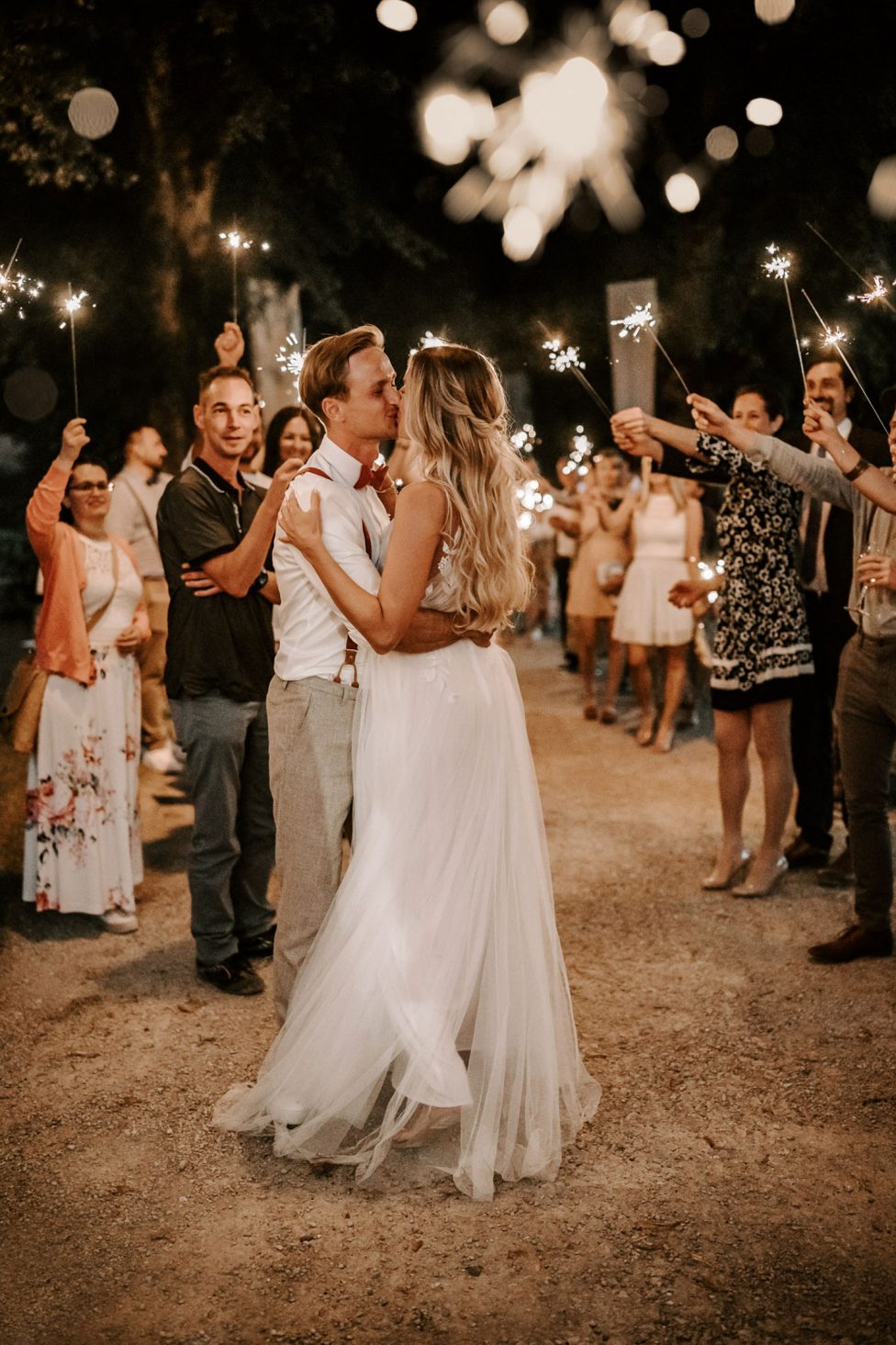 Hochzeitswahn - Braut und Bräutigam tanzen nachts im Freien einen romantischen Tanz, umgeben von Gästen mit Wunderkerzen in der Hand, und schaffen so unter Lichterketten eine zauberhafte Atmosphäre. Magical-Homes