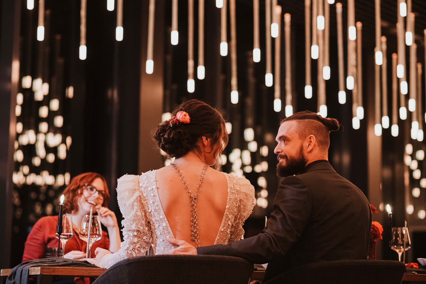 Hochzeitswahn - Ein Paar genießt einen intimen Moment an einem romantischen, schwach beleuchteten Ort, umgeben von Hängelampen, die eine Atmosphäre von Wärme und Eleganz schaffen.