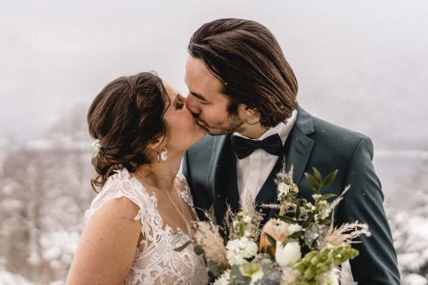Hochzeitswahn - Eine Braut und ein Bräutigam küssen sich im Schnee.
