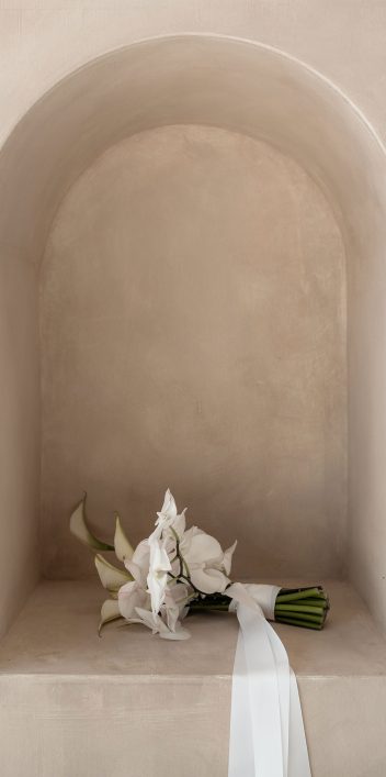 Hochzeitswahn - Auf einer Steinmauer liegt ein weißer Blumenstrauß.