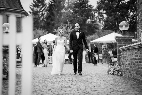 Hochzeitswahn - Eine Braut und ein Bräutigam gehen einen gepflasterten Weg entlang.