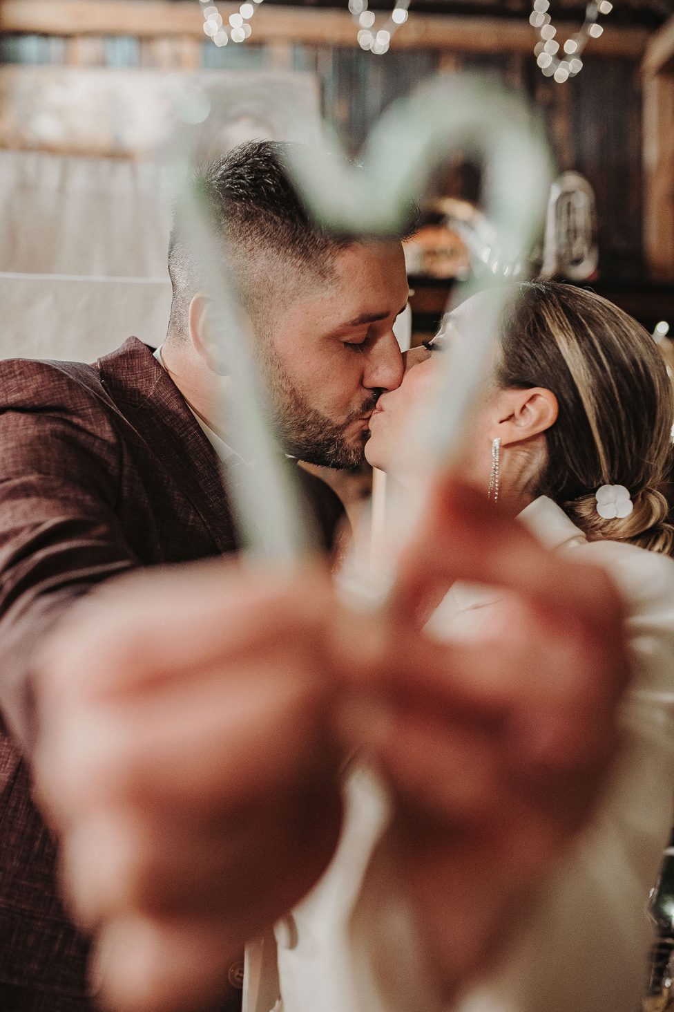 Hochzeitswahn - Eine Braut und ein Bräutigam küssen sich vor einem herzförmigen Rahmen.
